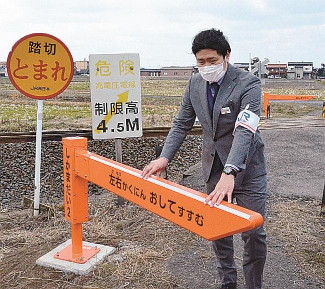 踏切ゲートを押して横断するＪＲ西日本社員＝米子市二本木、鹿間第２踏切