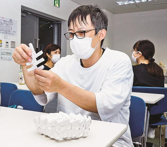 紙を組み合わせてかごを作る参加者＝松江市朝日町、松江テルサ