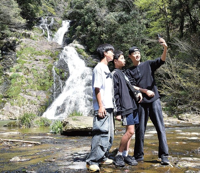 滝の近くで記念写真を撮る参加者=江津市波積町、岩瀧寺の滝