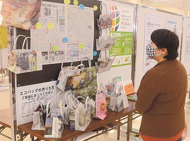 新聞紙で作られたエコバッグを見る来館者＝出雲市大塚町、ゆめタウン出雲