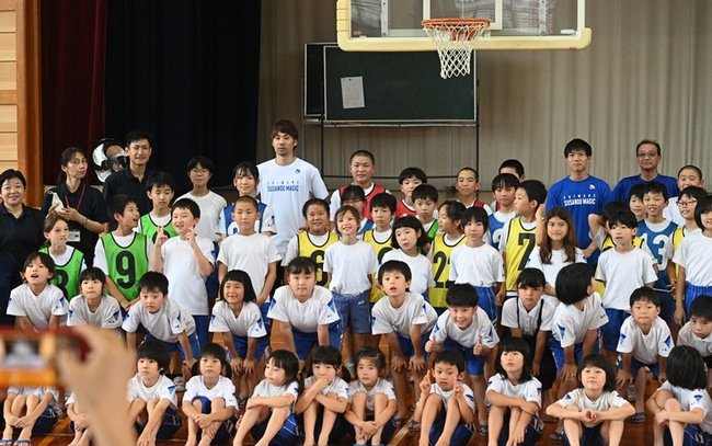 大橋大空選手（後列右から３人目）の「４引く２は？」の声に応えながら記念写真に収まる児童