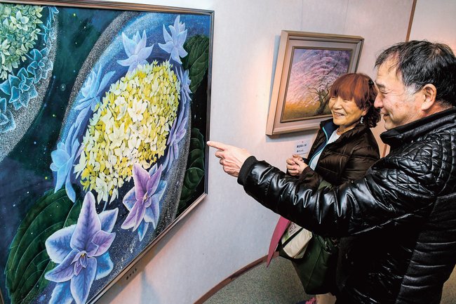 来場者に作品を解説する大森幹雄さん（右）＝出雲市西平田町、ギャラリー「ハンド＆ハンド」