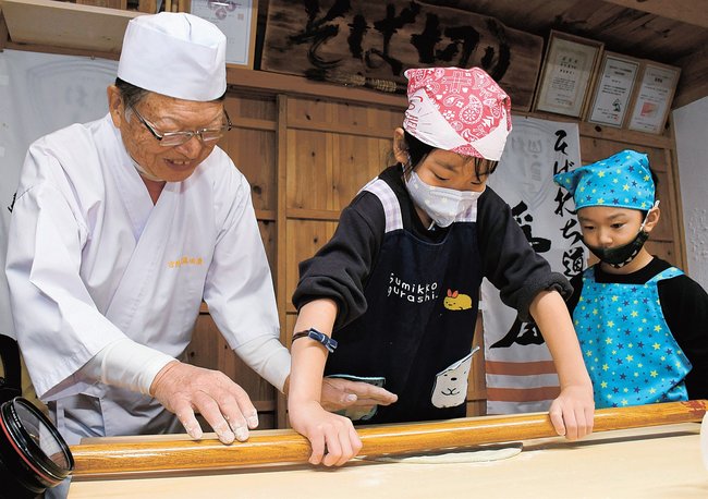 麺棒を使って生地を延ばし、そば打ちを体験する児童＝島根県邑南町井原