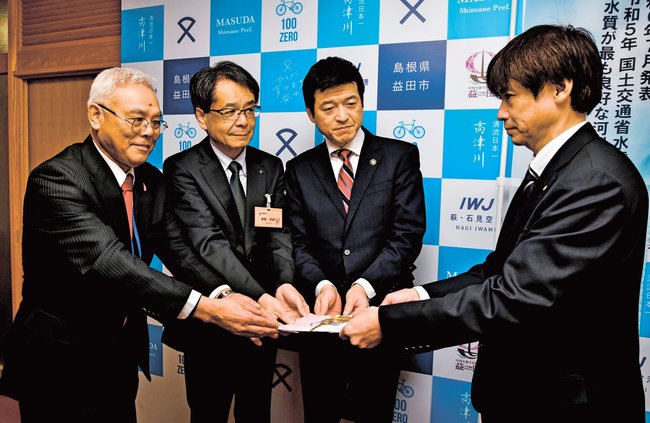 山本浩章益田市長（左から３人目）ら主催者に目録を手渡す山陰中央新報社の福井英樹西部本社代表（右）＝益田市常盤町、市役所