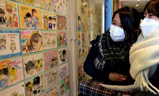 年賀状に見入る来場者＝鳥取県北栄町由良宿、青山剛昌ふるさと館