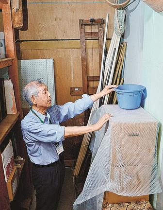 収蔵品の雨漏り対策をする浜田郷土資料館の小松原豊館長。浜田氏は新たな歴史資料館を代替施設に位置付ける＝浜田市黒川町