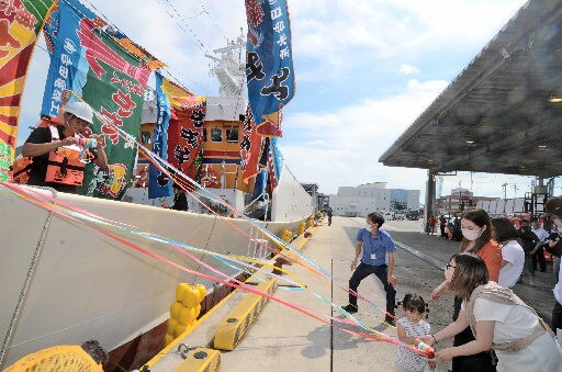 家族らが見送る中、出港準備をする「第六十八 かがみ丸」の乗組員(左)=境港市昭和町、境漁港