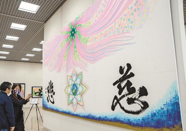 願いを込めた作品を来館者に解説する奥田迦侑さん（右）＝松江市袖師町、島根県立美術館