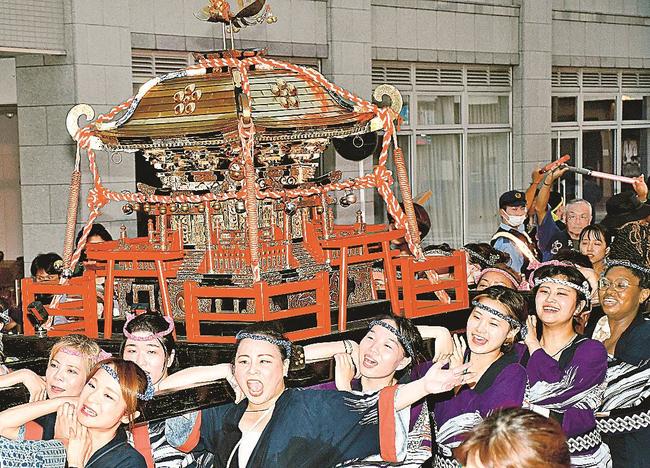 後方でおんなみこしを担ぐ記者（右から２人目）＝松江市殿町