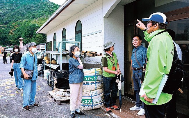 4代目の水族館だった建物前でガイド(右端)から解説を受ける参加者=松江市美保関町美保関