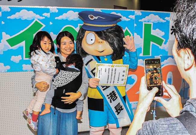 「一日空港長」の鬼太郎と一緒に記念撮影する家族＝境港市佐斐神町、米子空港