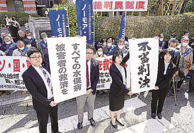 水俣病特別措置法に基づく救済策で対象外となった人たちが国などに損害賠償を求めた訴訟の判決で請求が棄却され、熊本地裁前で「不当判決」を訴える原告側の弁護士ら＝２２日、熊本市