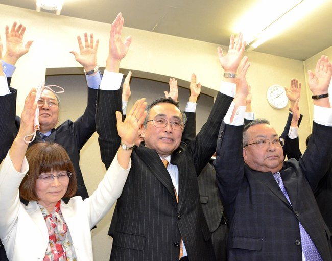 ３選を果たして支持者と万歳で喜ぶ深沢義彦氏（中央）＝２７日午後８時１０分、鳥取市新町の事務所