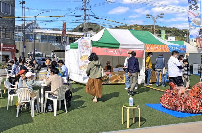 美郷町の「山くじらバーガー」などを販売するブースのそばで飲食を楽しむ家族連れら
