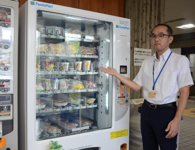 島根県で初めて設置されたファミリーマートの自販機と、管理担当の藤原裕二さん（49）＝松江市殿町、島根県庁南庁舎＝