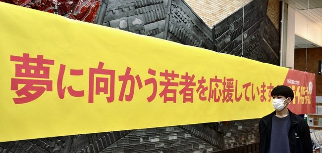 若者の門出を祝おうと掲げられた横断幕=松江市朝日町、JR松江駅
