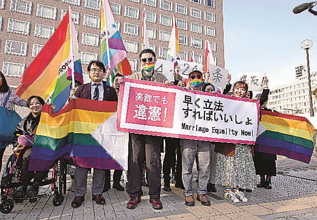 同性婚を巡る訴訟の控訴審判決を受け、札幌高裁前で「高裁でも違憲！」などと書かれたメッセージを掲げる原告ら＝１４日午後