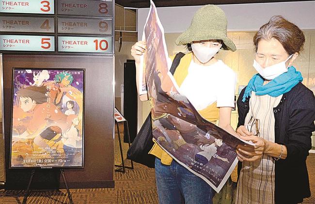 『神在月のこども』を特集したラッピング紙面を読む来場者＝出雲市大塚町、Ｔ・ジョイ出雲