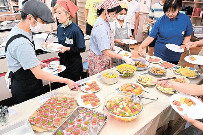 色とりどりのスイカ料理を取る参加者たち＝倉吉市上灘町、上灘コミュニティセンター