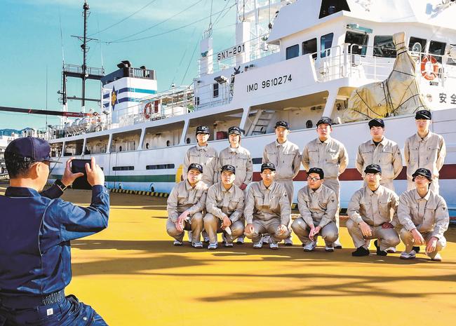 出港前に記念写真を撮影する隠岐水産高校専攻科の学生たち＝島根県隠岐の島町中町、西郷港