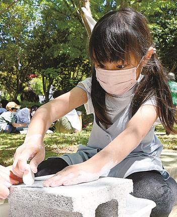 サンドペーパーで石を削り、勾玉の形に成形する児童＝松江市大庭町、八雲立つ風土記の丘