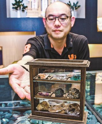 毎月届く天然石を紹介する新宮福志郎社長＝松江市玉湯町湯町、めのや