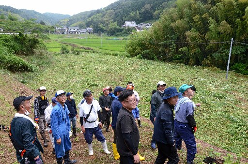 休耕田（中央）の草刈りをほぼ終え、くつろぐ参加者＝出雲市野郷町
