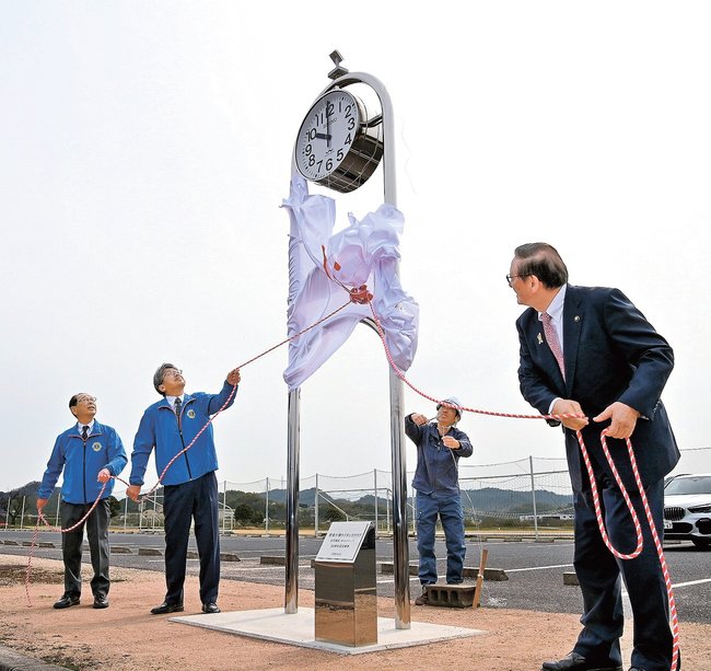 時計モニュメントの除幕をする板持伸一会長(左から2人目)ら=安来市穂日島町、中海ふれあい公園