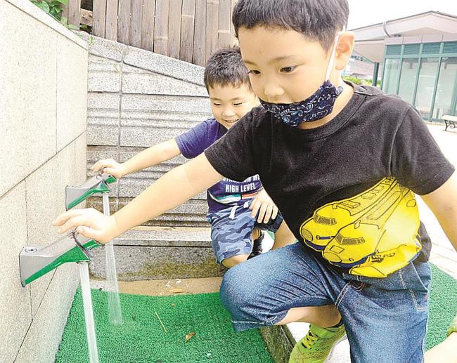 断水解消後、足洗い場の水を出す子ども＝出雲市多伎町多岐、道の駅キララ多伎