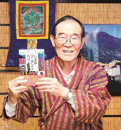 島根とブータン王国との交流の歴史をまとめた「しまね・ブータン王国物語」を手にする柳楽正雄さん＝出雲市日下町