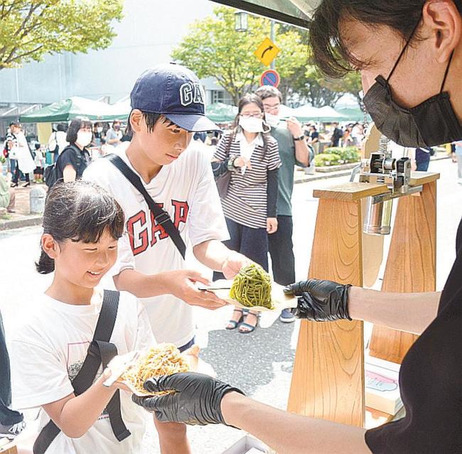 鳥取県産サツマイモ「紅はるか」などを使ったモンブランを受け取る来場者＝米子市末広町、米子コンベンションセンター前