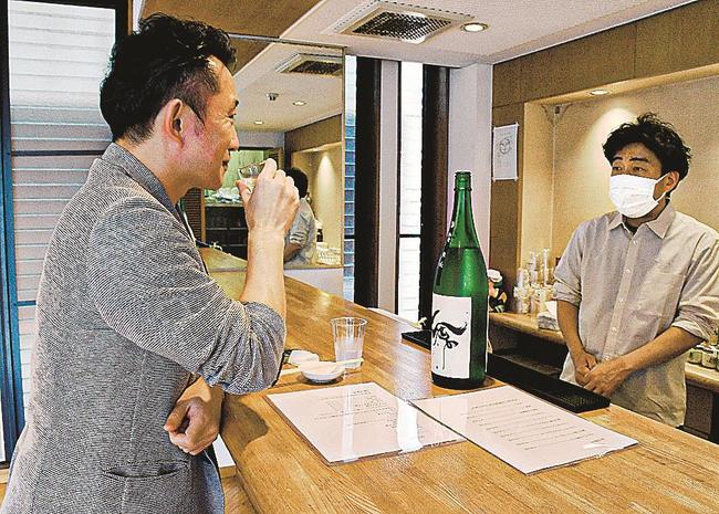 角打ちで全国の日本酒を楽しむ来店者（左）＝松江市東奥谷町、酒店・槙戸天狗堂