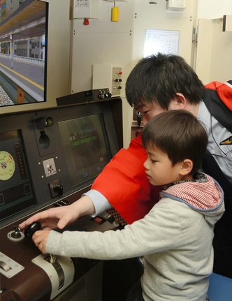 シミュレーターで列車の運転に挑戦する男の子（資料）
