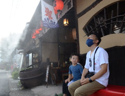 ミストが噴出する飲食店で涼む県外客=島根県津和野町後田