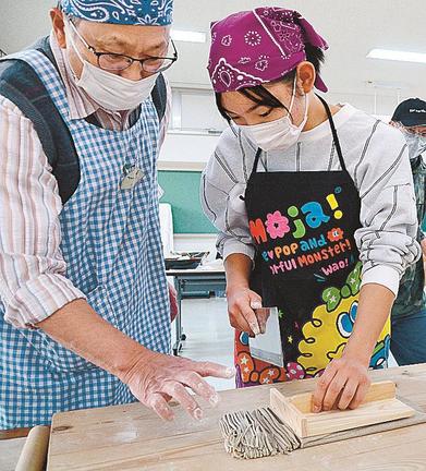 前田敏光会長（左）に教わりながら、そばを切る参加者＝安来市宇賀荘町、宇賀荘交流センター
