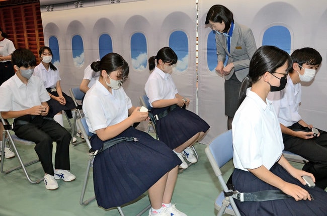 機内でのシートベルトの着脱方法を学ぶ生徒＝島根県吉賀町柿木、柿木中学校