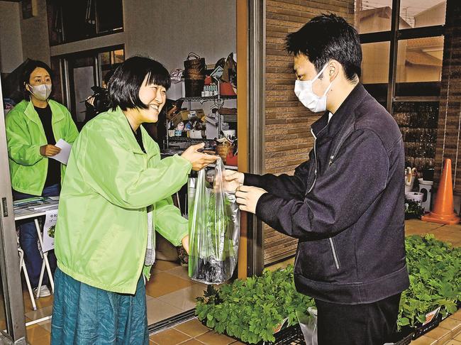 来店者にゴーヤーの苗を手渡す益田法人会員（左）＝益田市駅前町、フラワー湖月