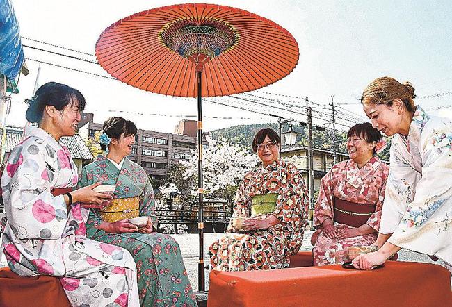 レンタルの着物で着飾り、玉湯川沿いの花見を楽しみながら、抹茶を味わう来場者＝松江市玉湯町玉造、玉造温泉ゆ～ゆ