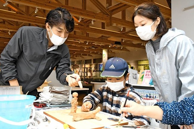 山下礼恵さん（右）の助言を受け、色づけする参加者＝島根県隠岐の島町中町、隠岐自然館
