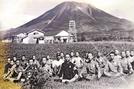 大山の麓にあった滑空訓練所で少年航空兵を目指した２期生の一部と教官（正面）ら。後方の建物は滑空機の倉庫や事務本部、宿舎棟などだった（１９４４年８月撮影、宇田川潔さん提供）