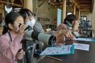 自然観察会に参加した小学生に指をさしながらカモの種類を説明する三原菜美さん＝米子水鳥公園