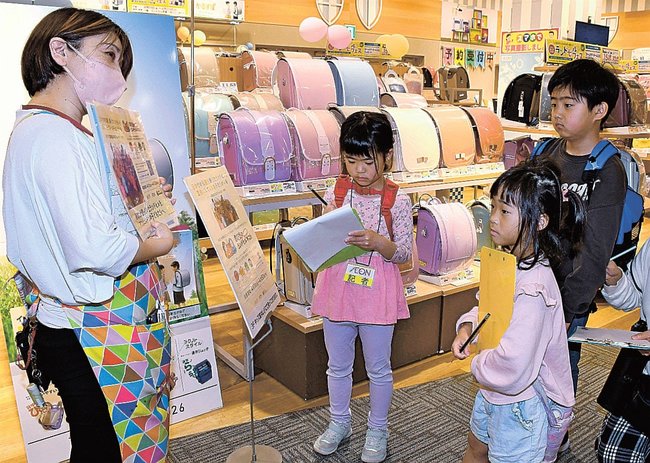 ランドセル売り場で担当者（左）に取材する子ども記者たち＝出雲市渡橋町、イオンスタイル出雲
