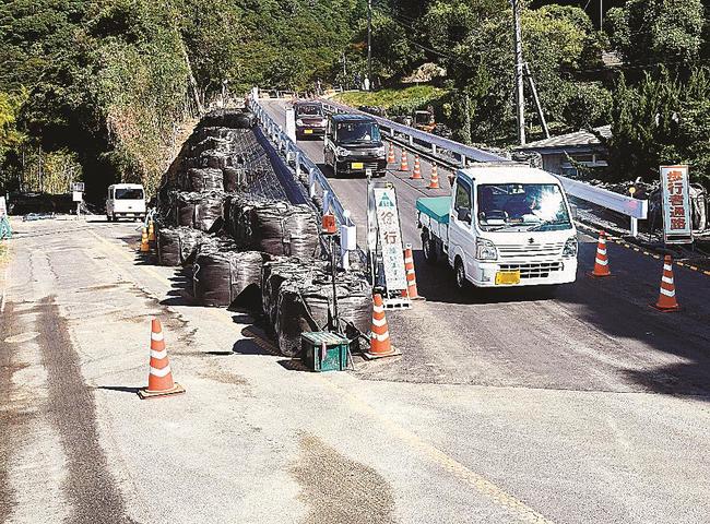 緊急車両用道路を通って地区外に出る住民の車両の列。左側が崩落現場＝11日午前９時ごろ、出雲市大社町日御碕