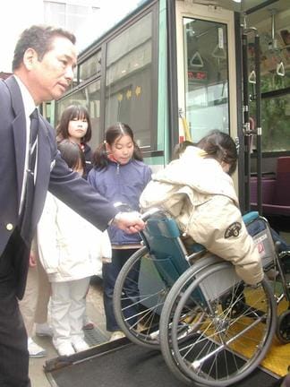総合学習の一環で、松江市交通局の職員（左）から車椅子によるバス利用について説明を受ける母衣小学校の児童＝２００２年２月、松江市内