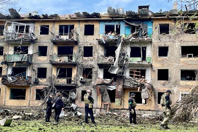 ４月３０日、ウクライナ東部ドネツク州で、ミサイル攻撃を受けた建物の周辺を調べるウクライナ兵ら（ロイター＝共同）