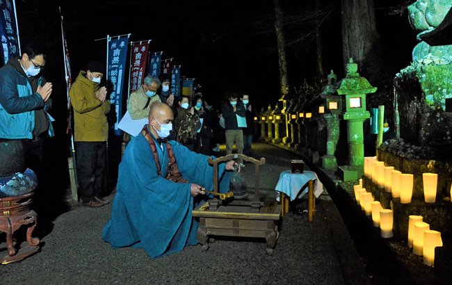 飯塚大幸管長(中央)が鳴らす鐘に合わせて祈りをささげる参加者=出雲市小境町、一畑薬師