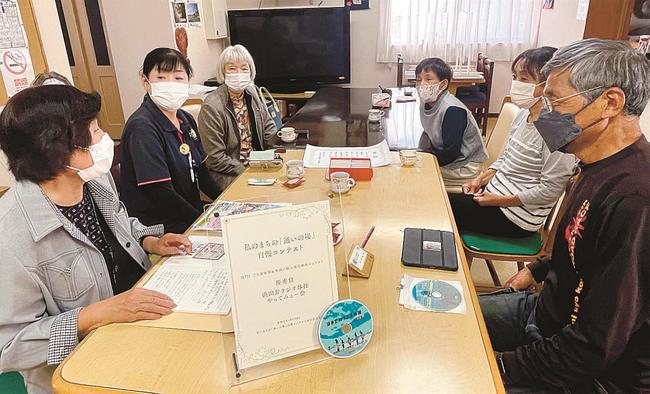 優秀賞の盾を囲み、はまだ弁ラジオ体操（唐鐘）の活用などを話し合うメンバー＝浜田市国分町、民宿しまや