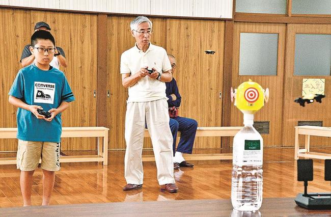 コントローラーでミニドローンを操作し的に見立てた風船に突進させる参加者＝江津市有福温泉町、有福温泉地域コミュニティ交流センター