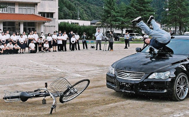 生徒の前で交通事故を再現するスタントマン(手前右端)=雲南市掛合町掛合、掛合中学校