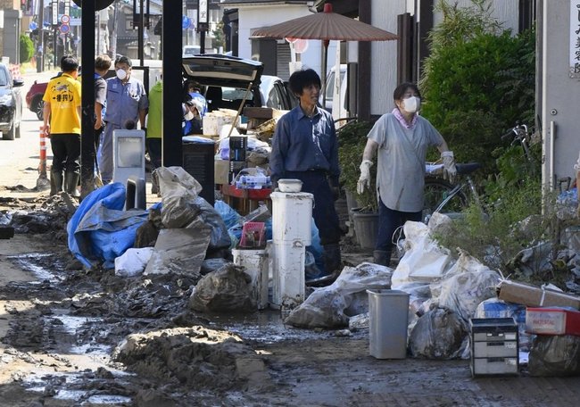 豪雨で冠水し泥に覆われた石川県輪島市で片付けに追われる人たち＝２５日午前